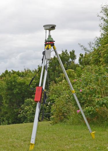 Geländescanner auf Wiese vor Büschen
