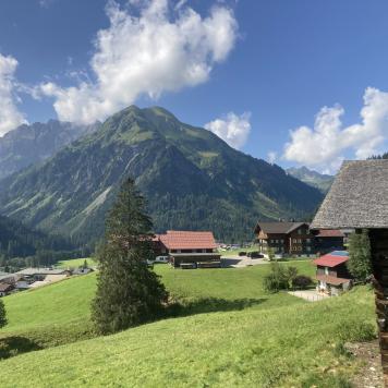 Häuser vor Bergpanorama in den Alpen bei blauem Himmel
