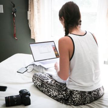 Frau sitzend mit auf Bett mit Laptop